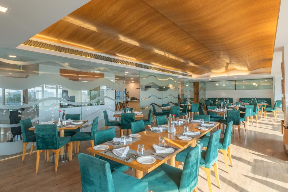 a restaurant with wooden tables and green chairs at Sunday Hotel Jaipur in Jaipur