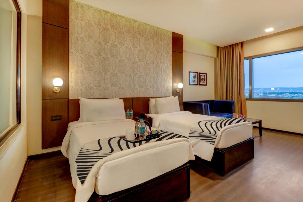 a hotel room with two beds and a window at Sunday Hotel Jaipur in Jaipur