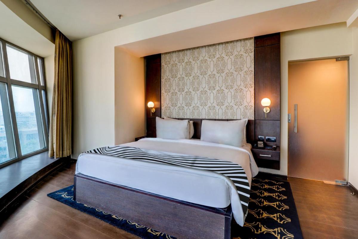 a bedroom with two beds and a large window at Sunday Hotel Jaipur in Jaipur