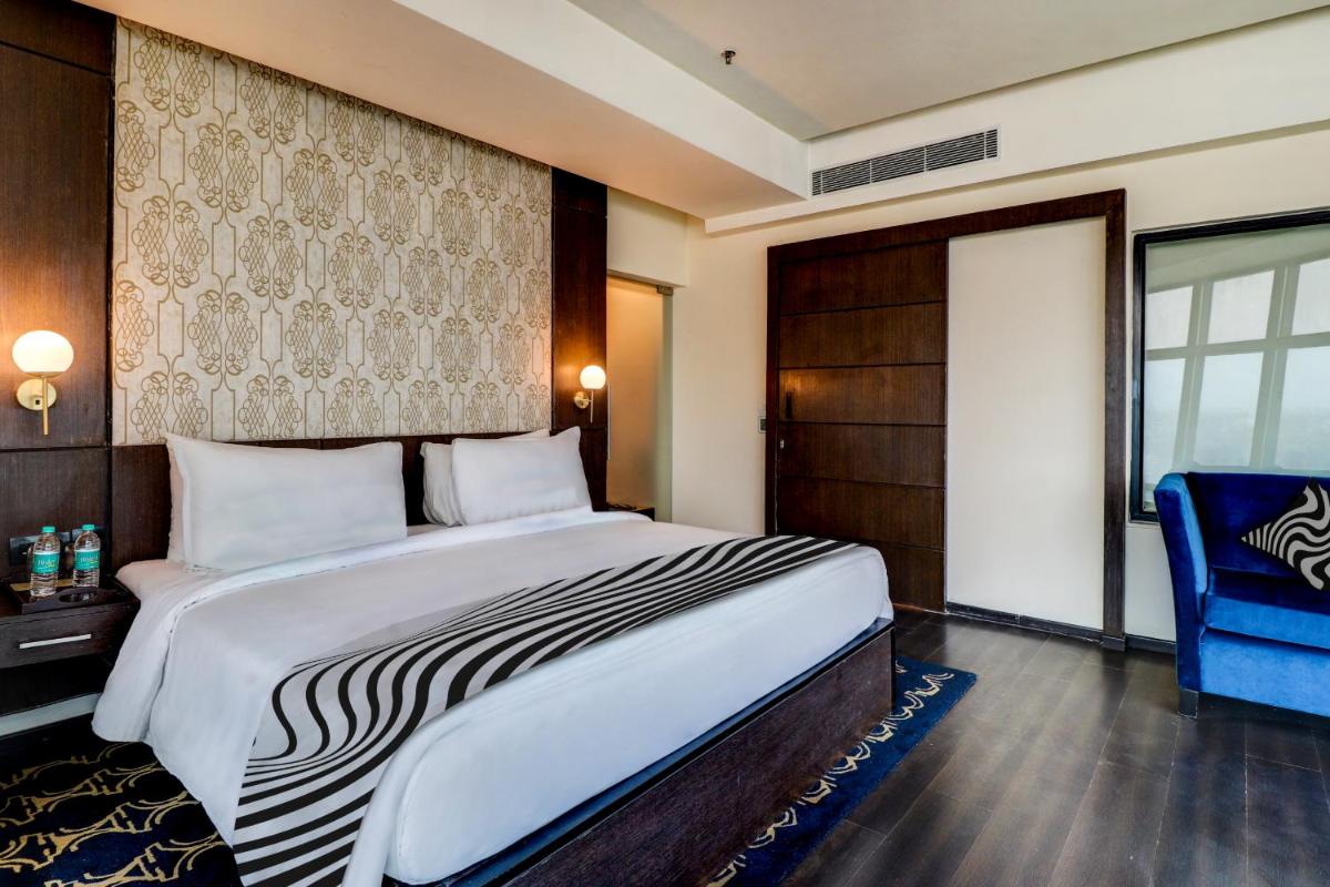 a bedroom with a large bed and a blue chair at Sunday Hotel Jaipur in Jaipur