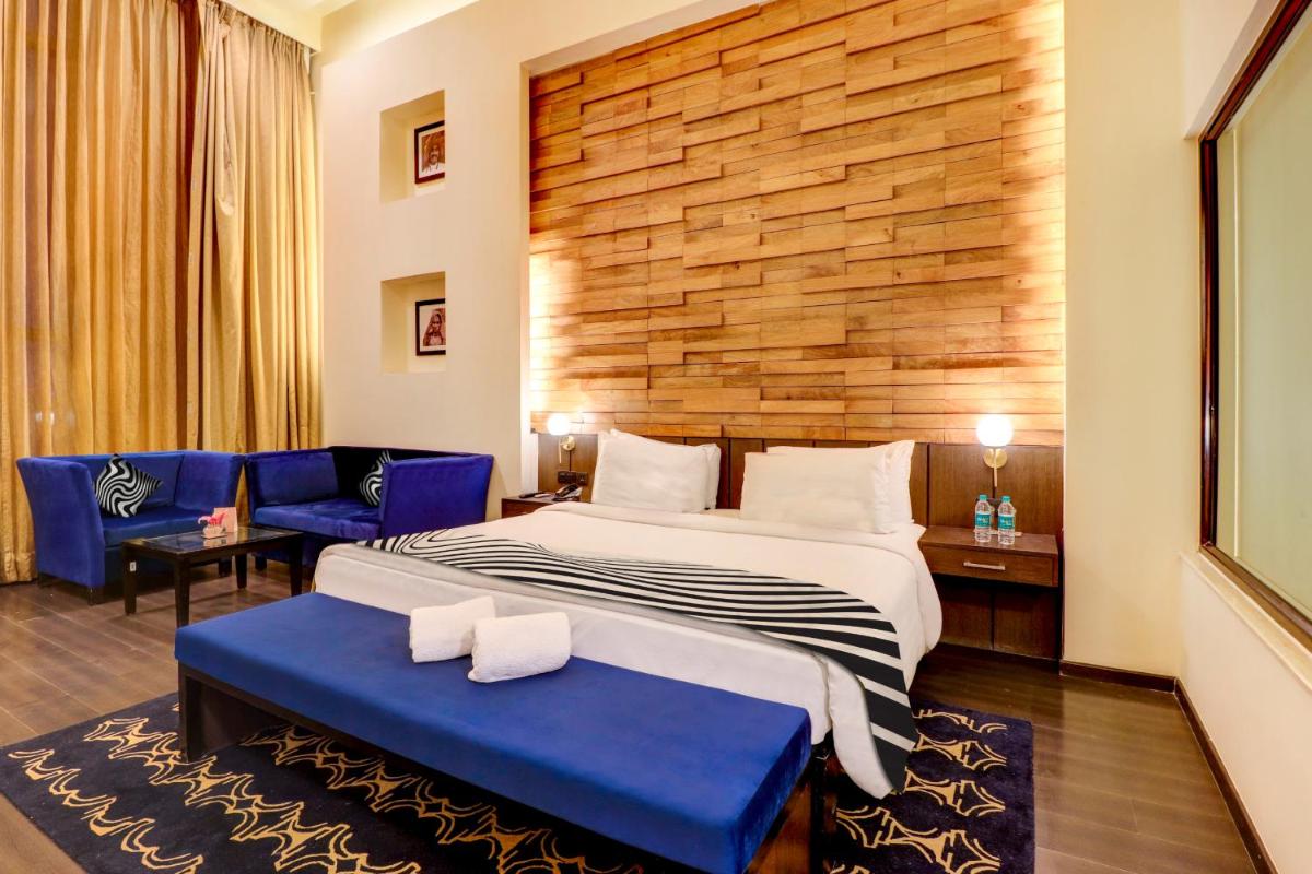 a hotel room with a large bed and blue chairs at Sunday Hotel Jaipur in Jaipur