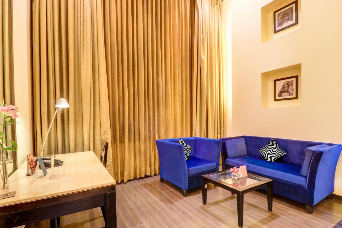 a living room with a blue couch and a table at Sunday Hotel Jaipur in Jaipur