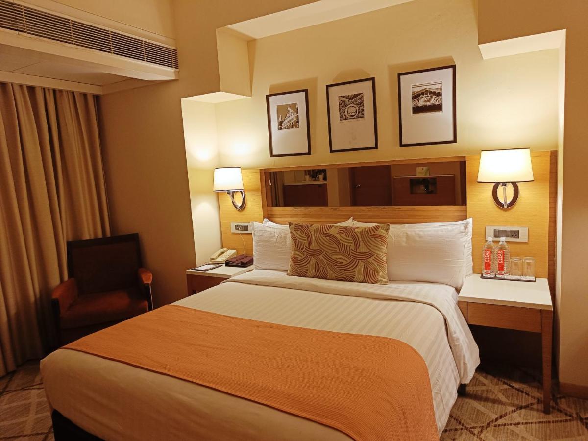a hotel room with a large bed and a chair at Hotel Marine Plaza in Mumbai