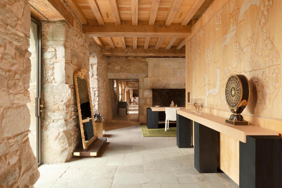 Cette grande chambre est dotée d'un mur en pierre avec une table. dans l'établissement HOTEL Domaine des Etangs, Auberge Resorts Collection, à Massignac