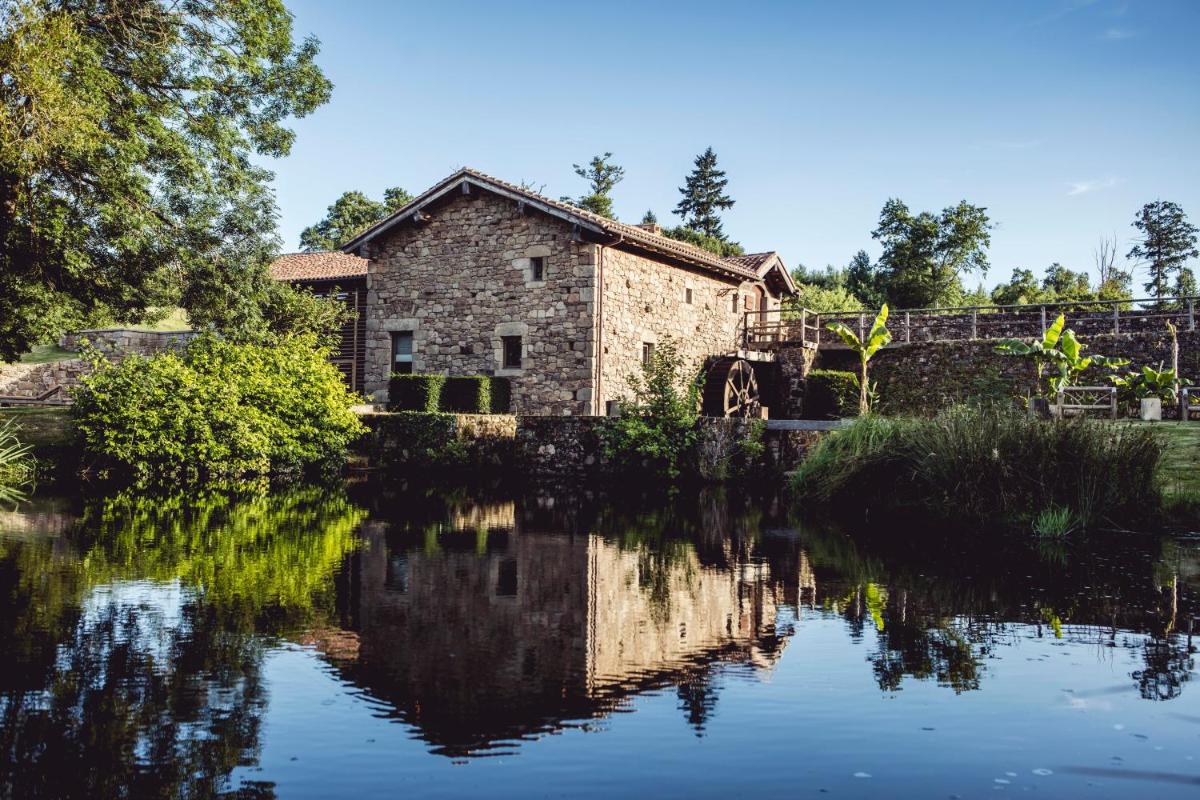 - un vieux bâtiment en pierre à côté d'une étendue d'eau dans l'établissement HOTEL Domaine des Etangs, Auberge Resorts Collection, à Massignac