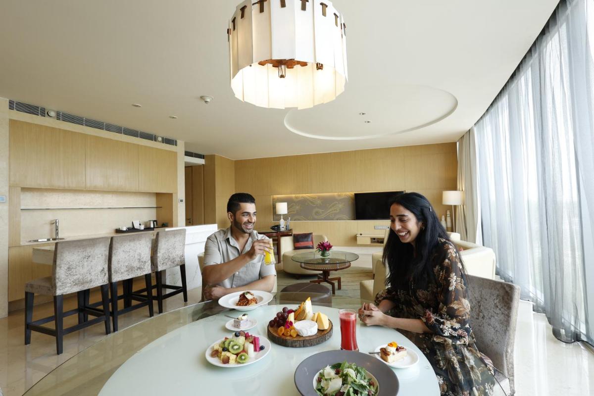 a man and a woman sitting at a table with food at The Westin Gurgaon, New Delhi in Gurgaon