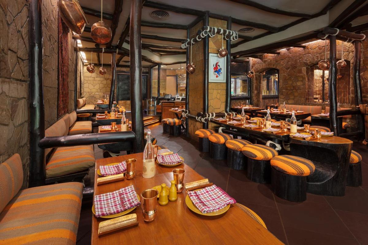 a restaurant with wooden tables and chairs in a room at ITC Maurya, a Luxury Collection Hotel, New Delhi in New Delhi a restaurant with wooden tables and chairs in a room at ITC Maurya, a Luxury Collection Hotel, New Delhi in New Delhi