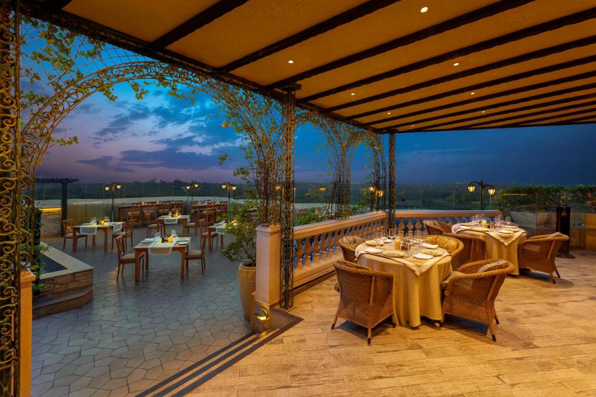 a restaurant with tables and chairs on a balcony at ITC Maurya, a Luxury Collection Hotel, New Delhi in New Delhi a restaurant with tables and chairs on a balcony at ITC Maurya, a Luxury Collection Hotel, New Delhi in New Delhi