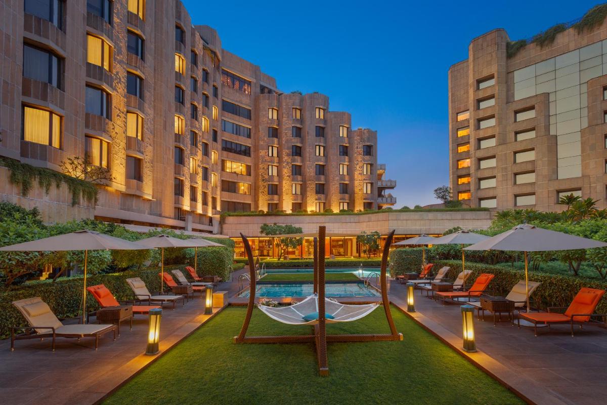 a courtyard with chairs and umbrellas and a pool at ITC Maurya, a Luxury Collection Hotel, New Delhi in New Delhi a courtyard with chairs and umbrellas and a pool at ITC Maurya, a Luxury Collection Hotel, New Delhi in New Delhi