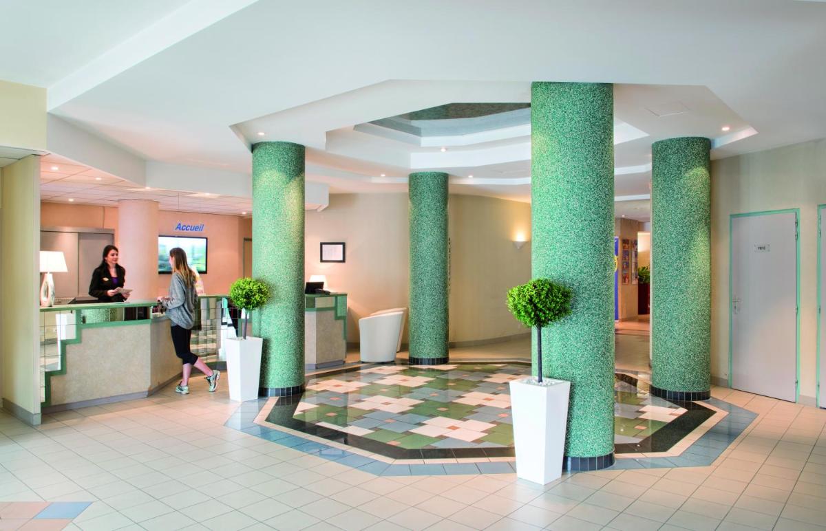 le hall d'un hôtel avec des colonnes et des plantes dans l'établissement Hotel *** & Spa Vacances Bleues Villa Marlioz, à Aix-les-Bains 51 autres photos