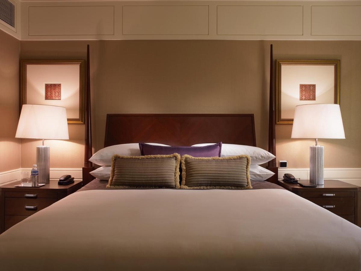 a bedroom with a large bed with two lamps at The Leela Mumbai in Mumbai a bedroom with a large bed with two lamps at The Leela Mumbai in Mumbai