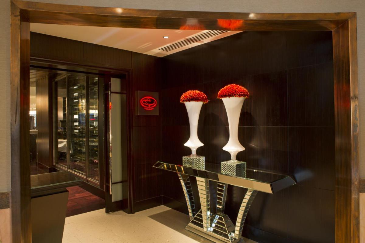 two vases with red flowers on a table in a lobby at The Leela Mumbai in Mumbai two vases with red flowers on a table in a lobby at The Leela Mumbai in Mumbai