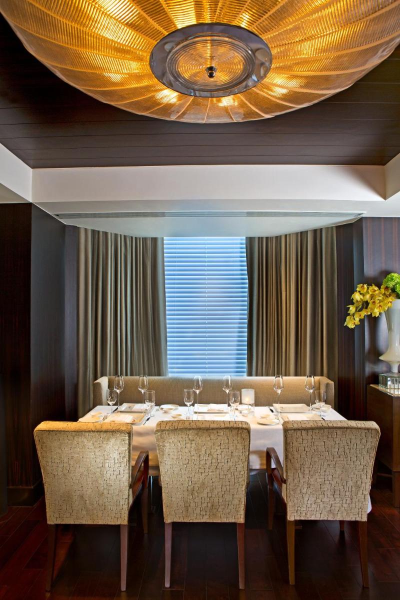 a dining room with a table with chairs and a ceiling at The Leela Mumbai in Mumbai a dining room with a table with chairs and a ceiling at The Leela Mumbai in Mumbai