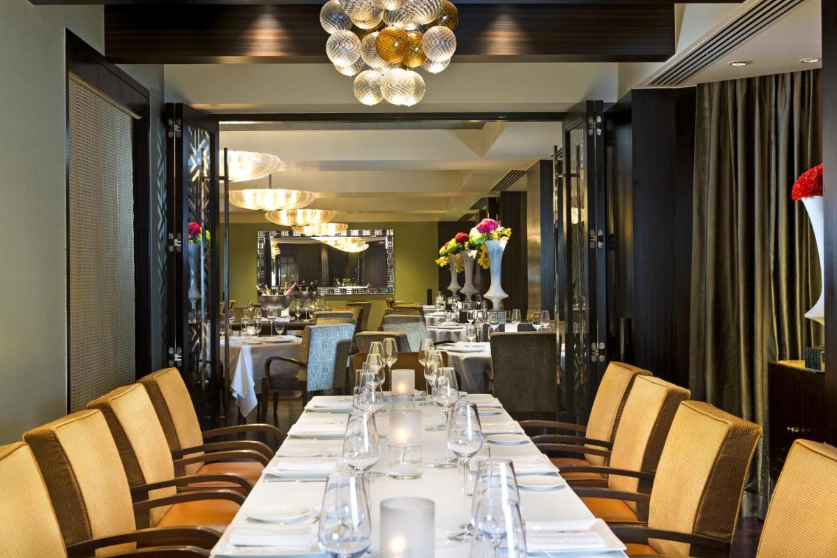a dining room with a long table and chairs at The Leela Mumbai in Mumbai a dining room with a long table and chairs at The Leela Mumbai in Mumbai