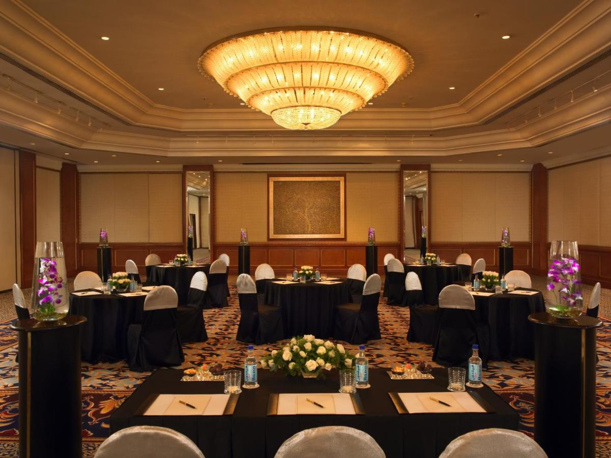 a ballroom with tables and chairs and a chandelier at The Leela Mumbai in Mumbai a ballroom with tables and chairs and a chandelier at The Leela Mumbai in Mumbai