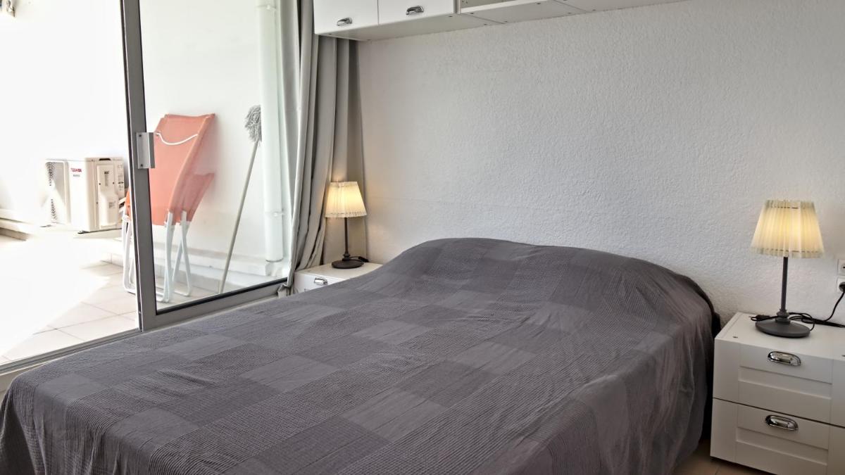 une chambre avec un lit et un grand miroir dans l'établissement Residence Ulysse Port Camargue, au Grau-du-Roi