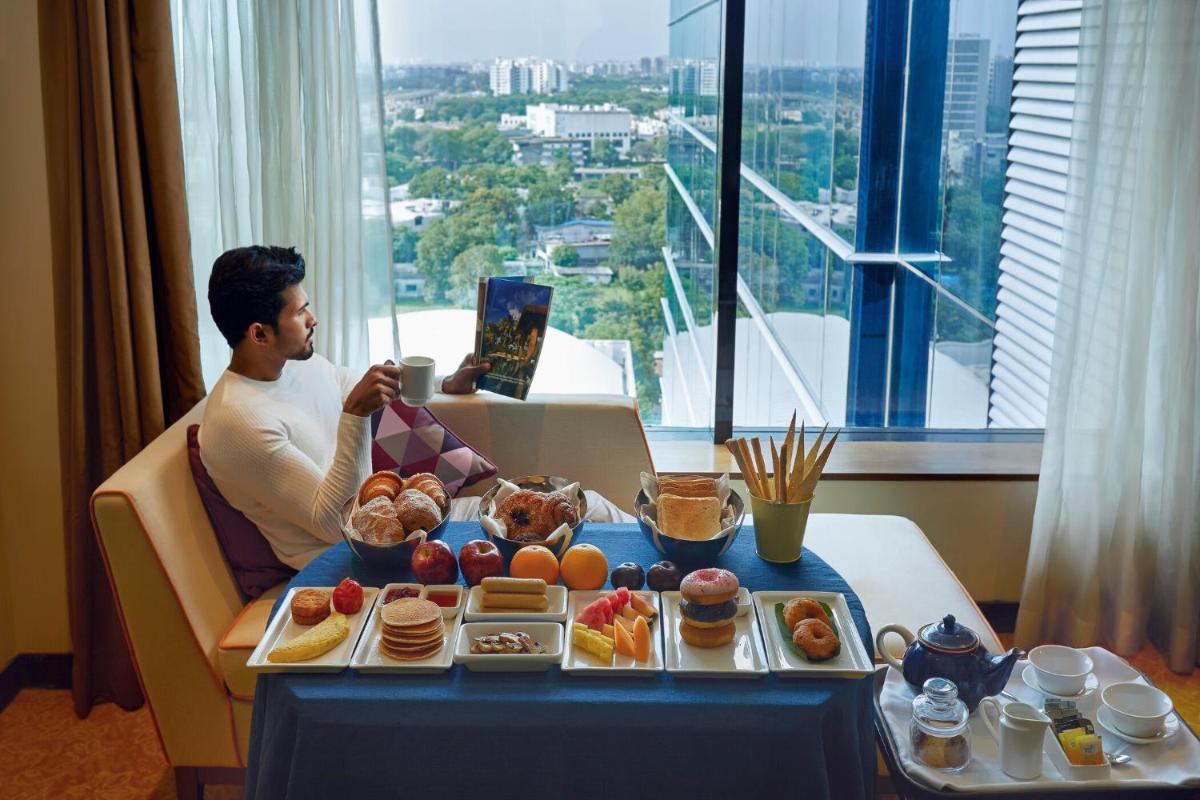 a man sitting at a table with a tray of food at Renaissance Ahmedabad Hotel in Ahmedabad