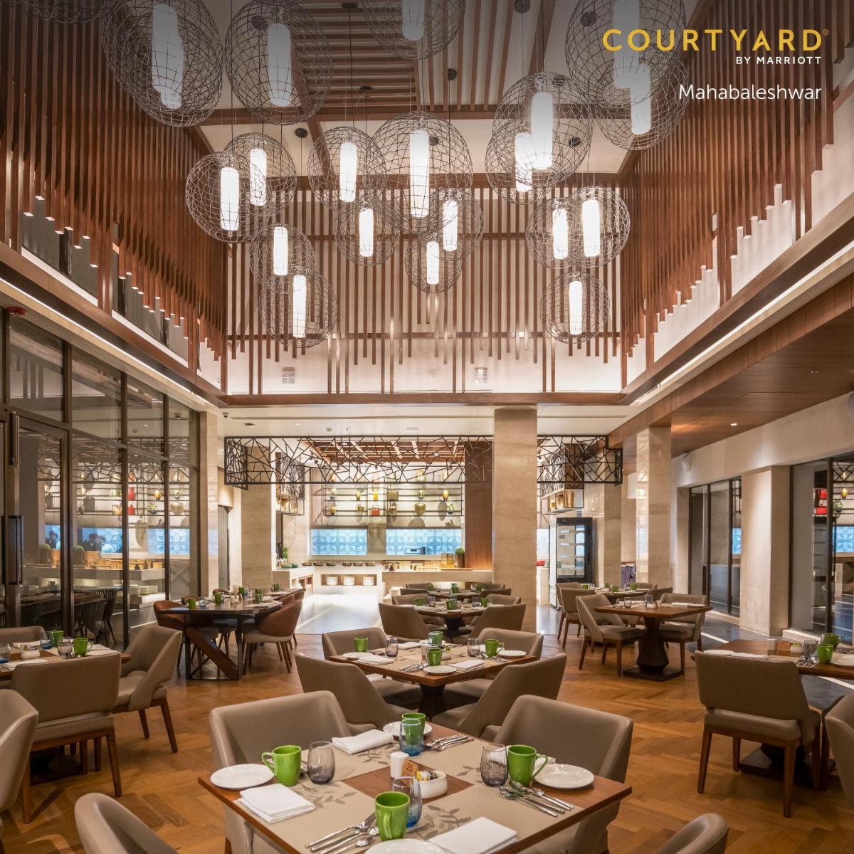 a restaurant with tables and chairs and a chandelier at Courtyard by Marriott Mahabaleshwar in Mahabaleshwar