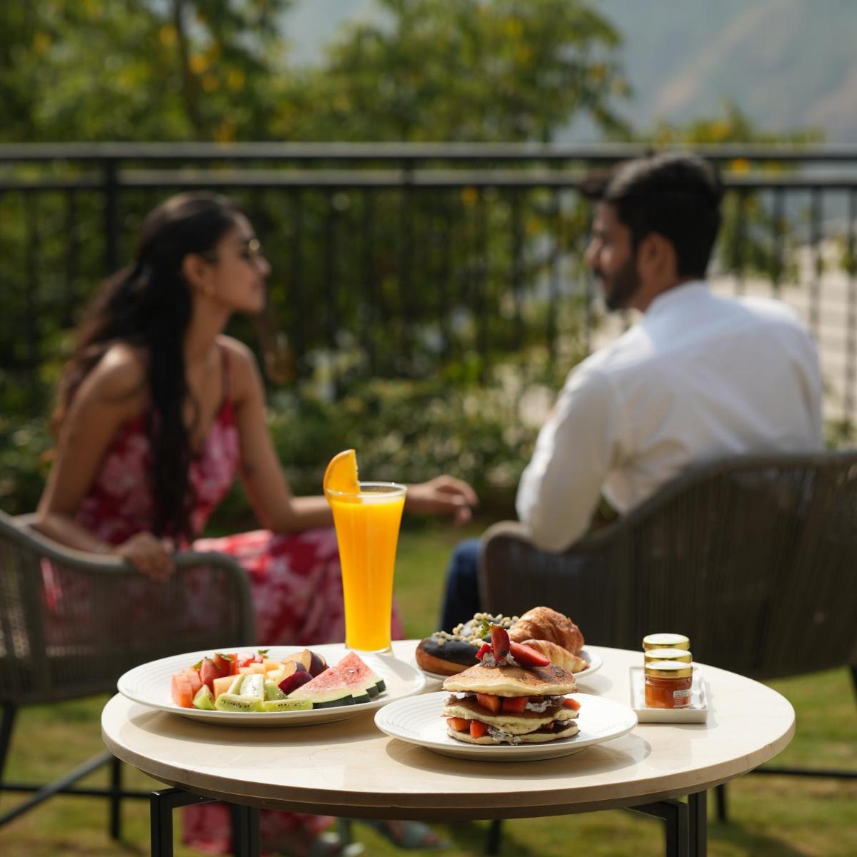 a man and woman sitting at a table with plates of food at Courtyard by Marriott Mahabaleshwar in Mahabaleshwar