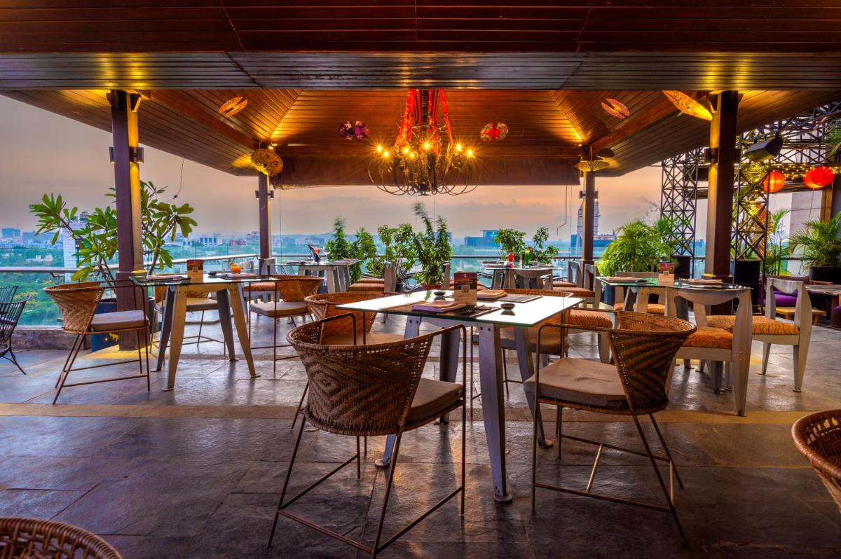 a restaurant with tables and chairs and a view of the ocean at O Hotel Pune in Pune