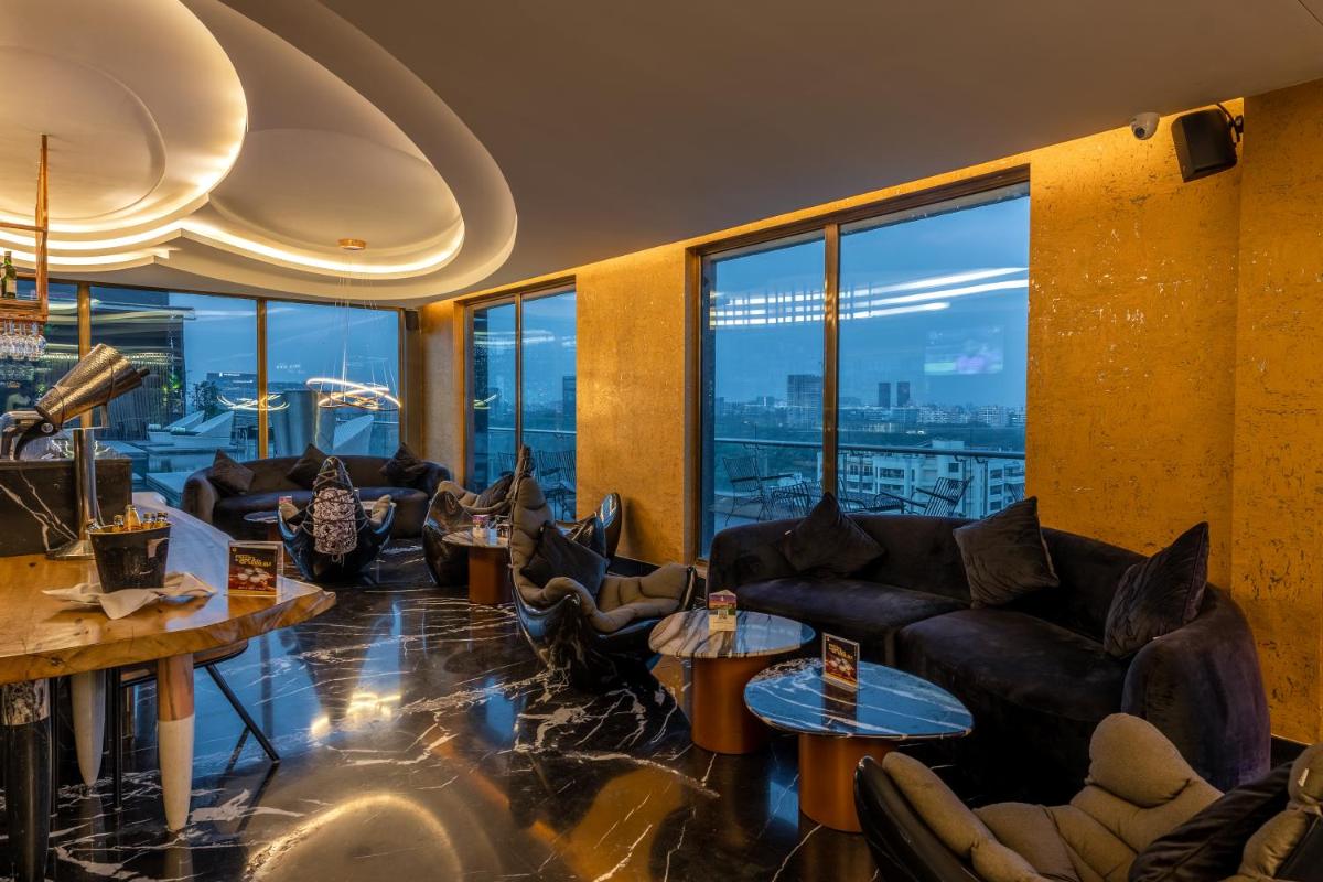 a living room with couches and tables and windows at O Hotel Pune in Pune