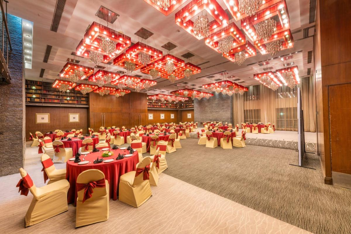 a banquet hall with tables and chairs and chandeliers at O Hotel Pune in Pune