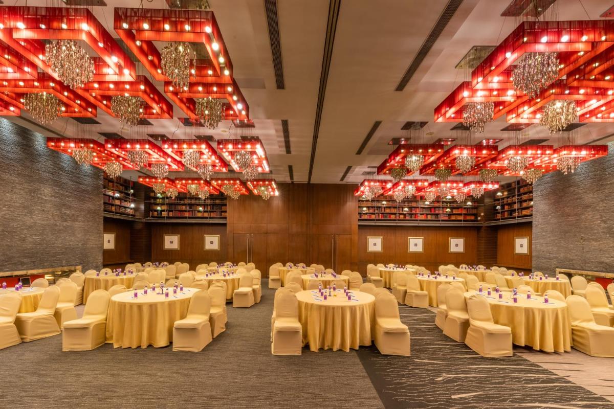 a banquet hall with tables and chairs and chandeliers at O Hotel Pune in Pune