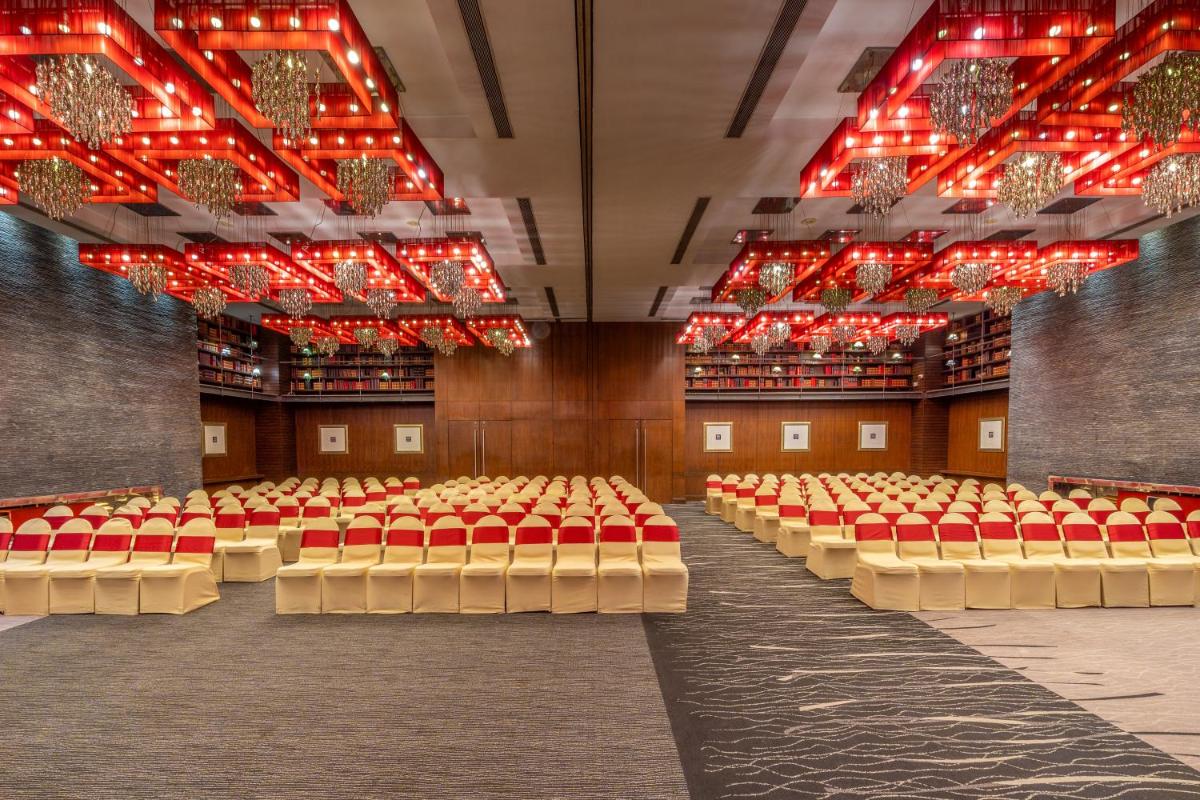 an empty room with red chairs and lights at O Hotel Pune in Pune