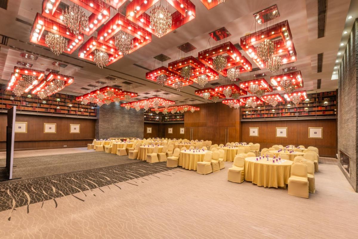a banquet hall with tables and chairs and chandeliers at O Hotel Pune in Pune