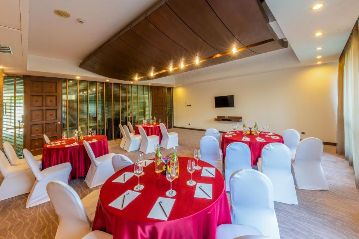 a banquet hall with red and white tables and white chairs at O Hotel Pune in Pune