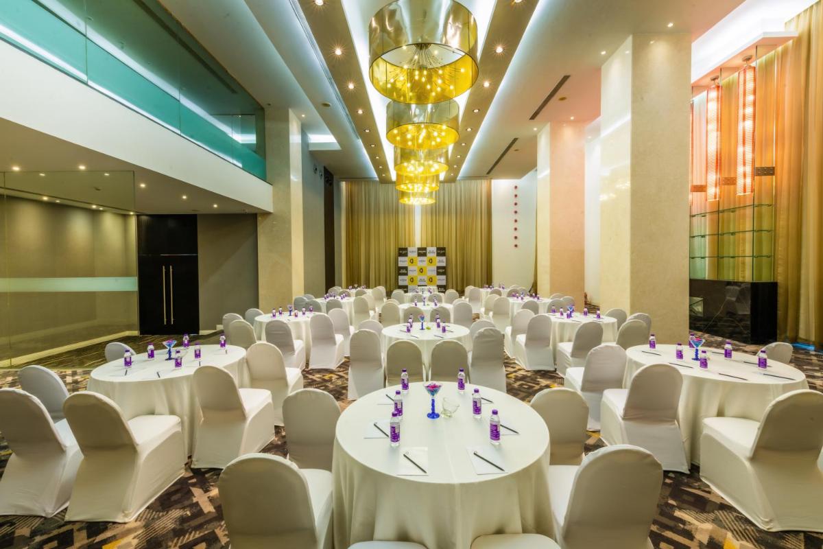 a conference room with white tables and chairs and a chandelier at O Hotel Pune in Pune