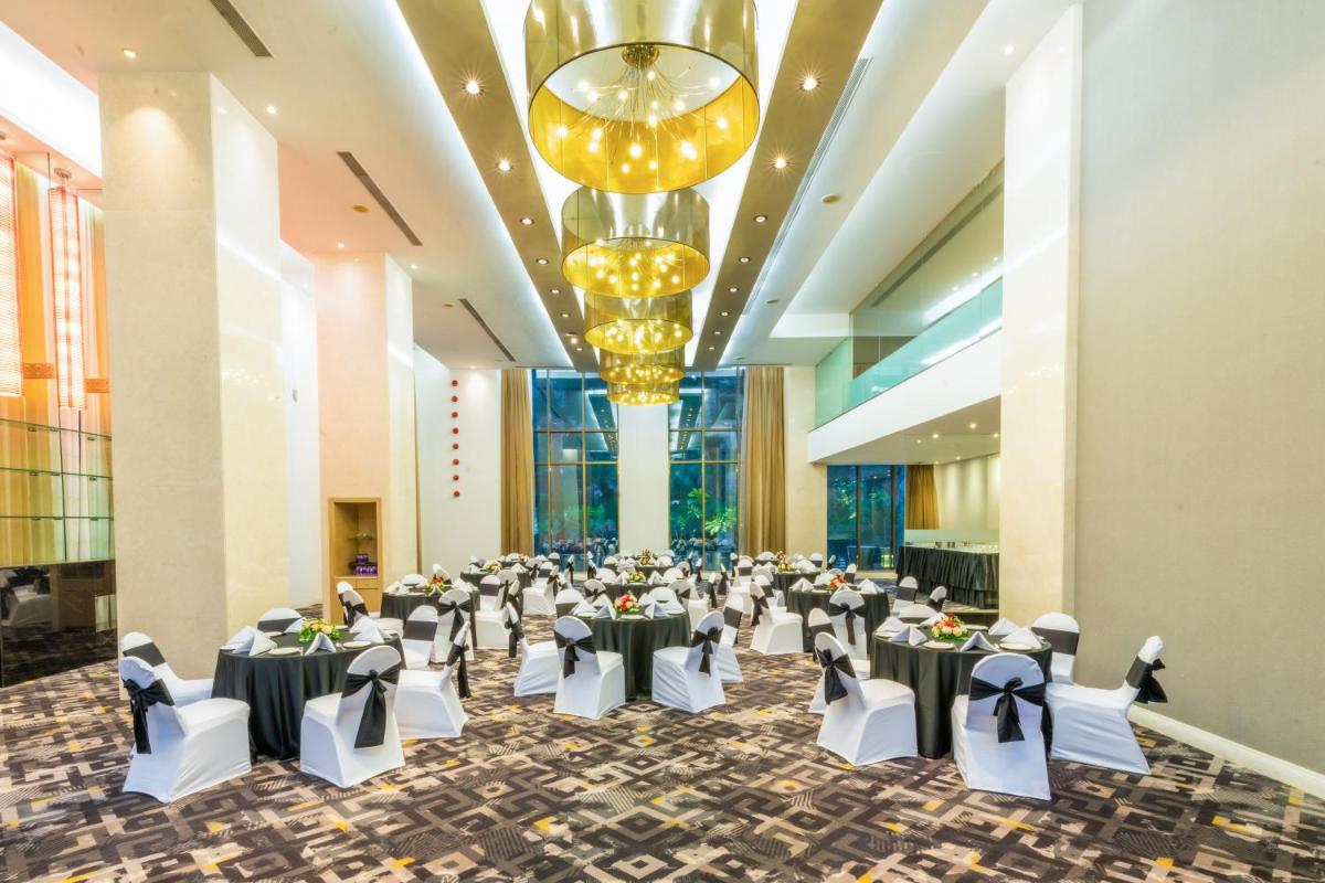 a banquet hall with tables and chairs and a chandelier at O Hotel Pune in Pune
