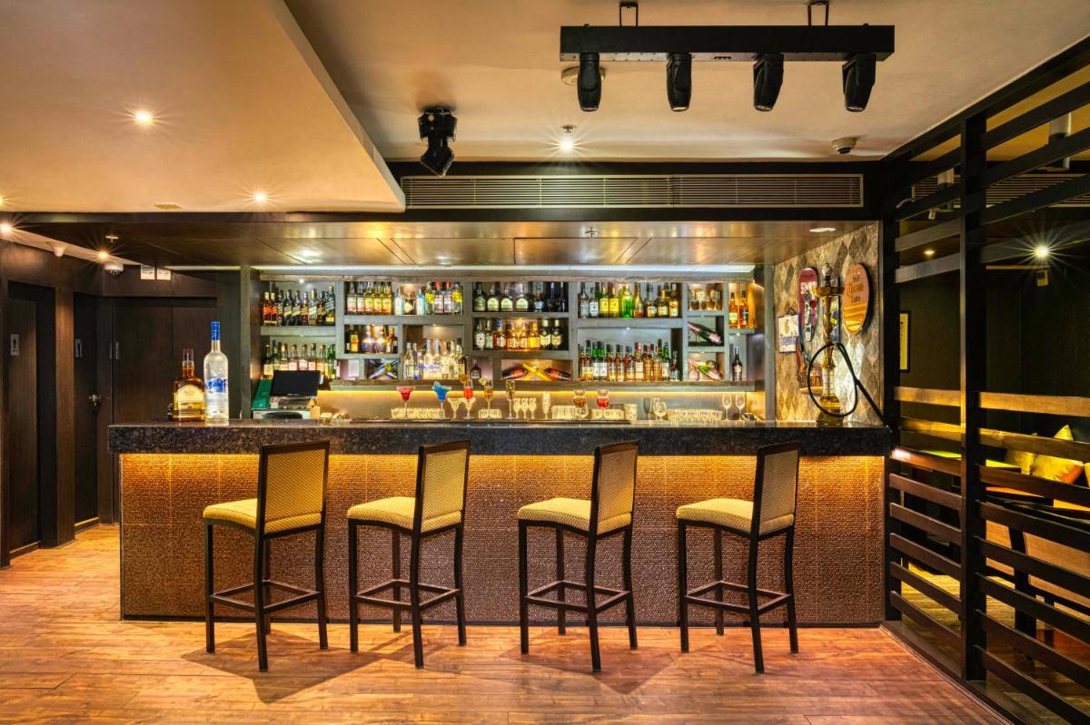 a bar with stools in a room with alcohol at Holiday Inn Kolkata Airport by IHG in Kolkata