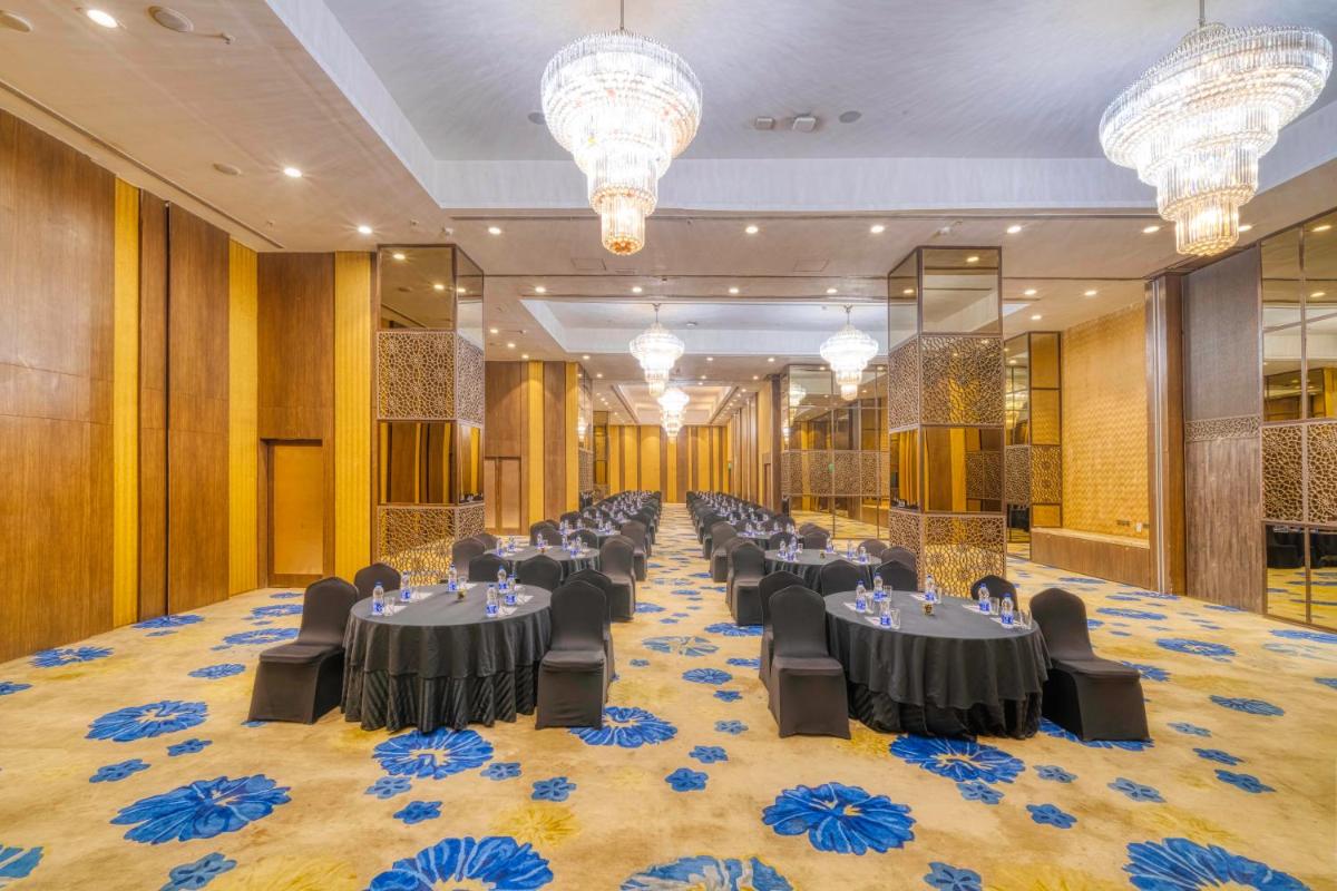 a banquet hall with tables and chairs and chandeliers at Holiday Inn Kolkata Airport by IHG in Kolkata