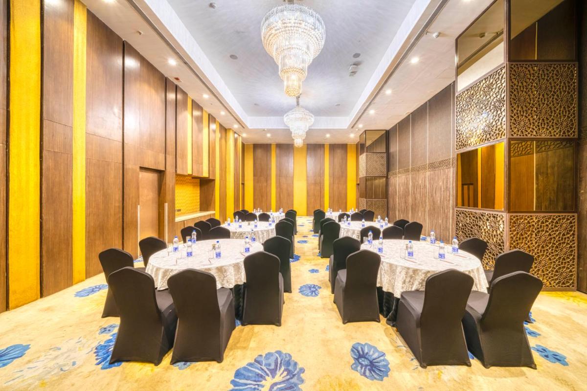 a conference room with tables and chairs and a chandelier at Holiday Inn Kolkata Airport by IHG in Kolkata