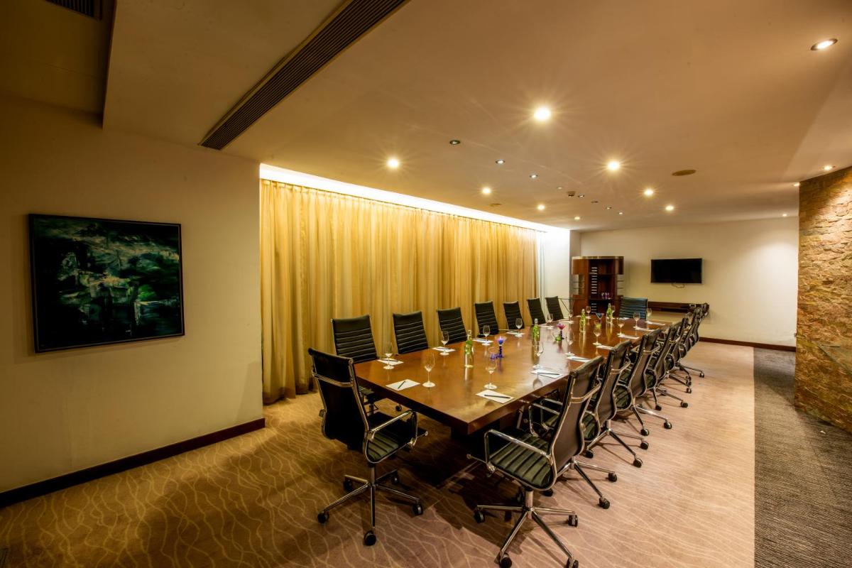 a long dining room with a long table and chairs at O Hotel Pune in Pune