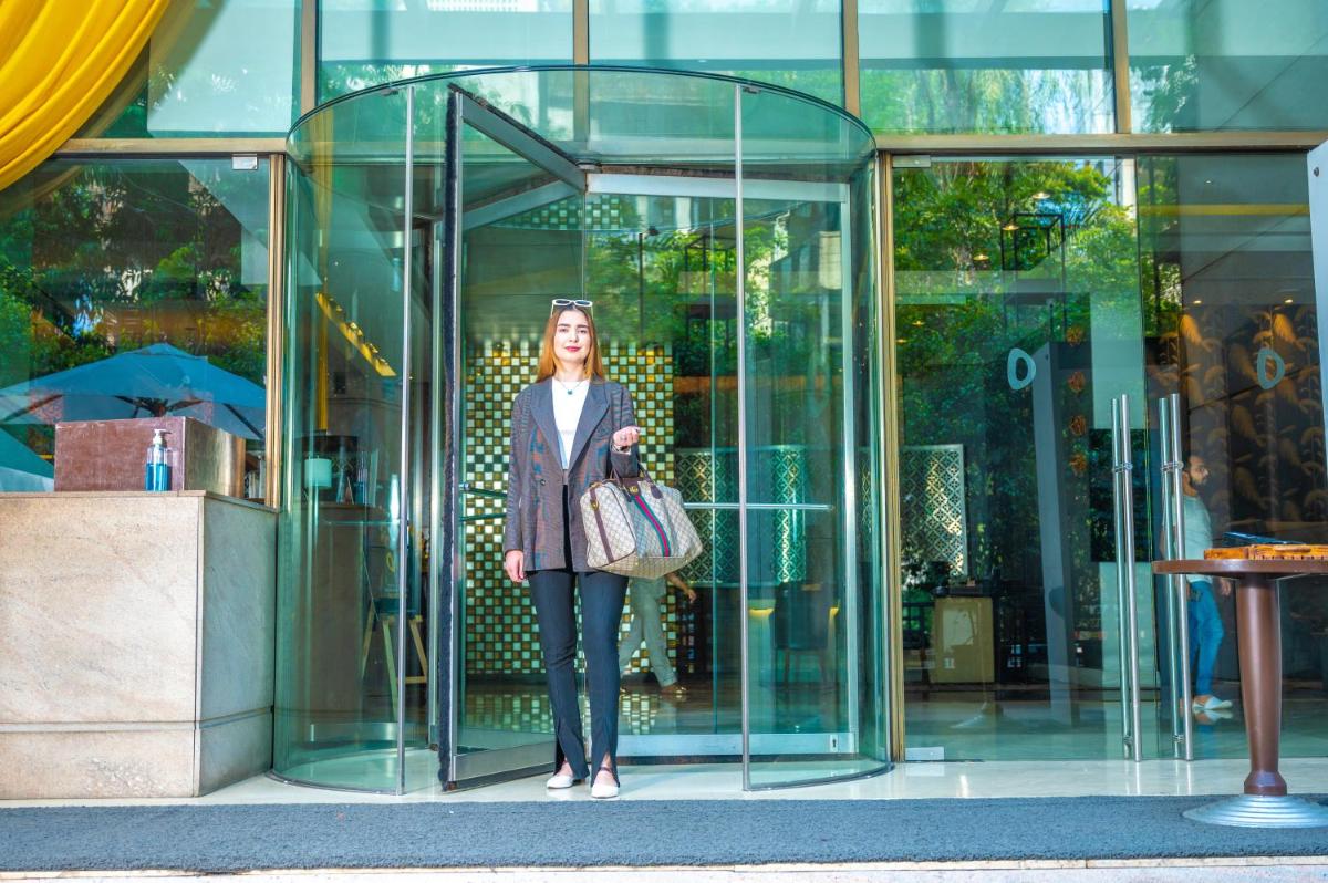 a woman standing outside of a glass building at O Hotel Pune in Pune