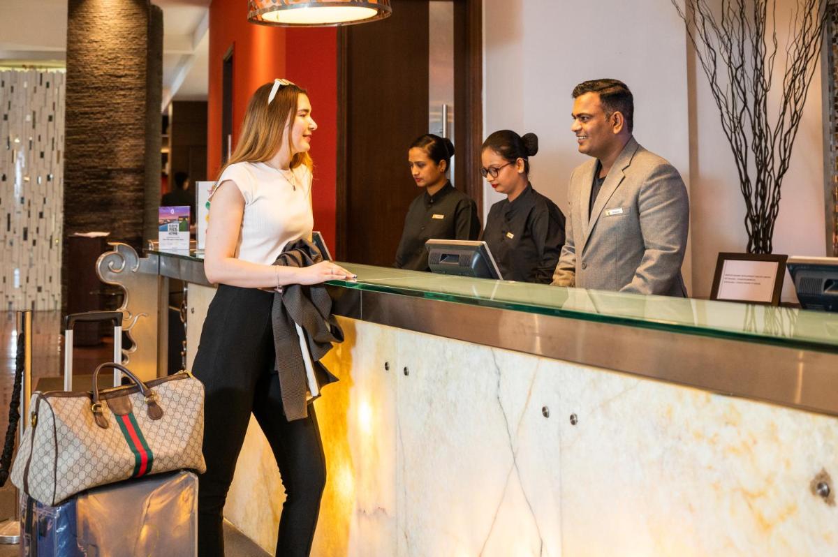 a woman standing next to a counter in a store at O Hotel Pune in Pune