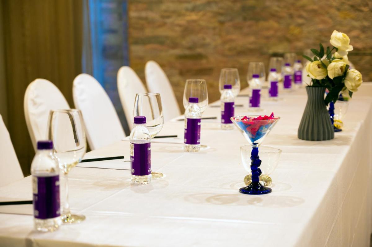 a long table with wine glasses and flowers on it at O Hotel Pune in Pune