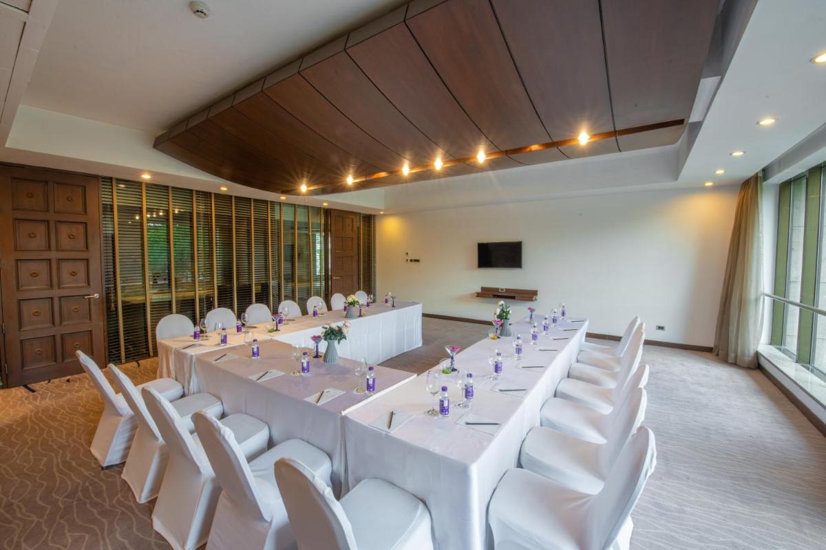 a large room with a long table and white chairs at O Hotel Pune in Pune