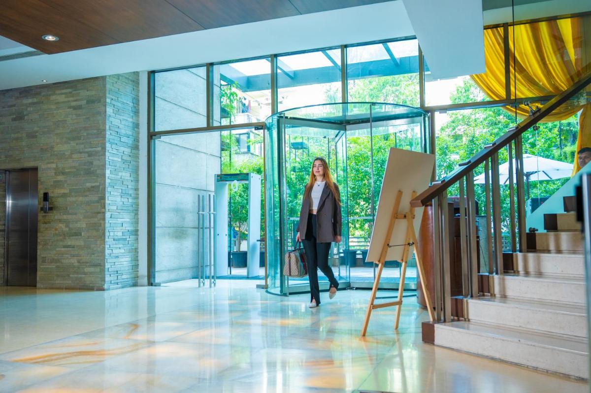 a woman walking down a hallway in a building at O Hotel Pune in Pune