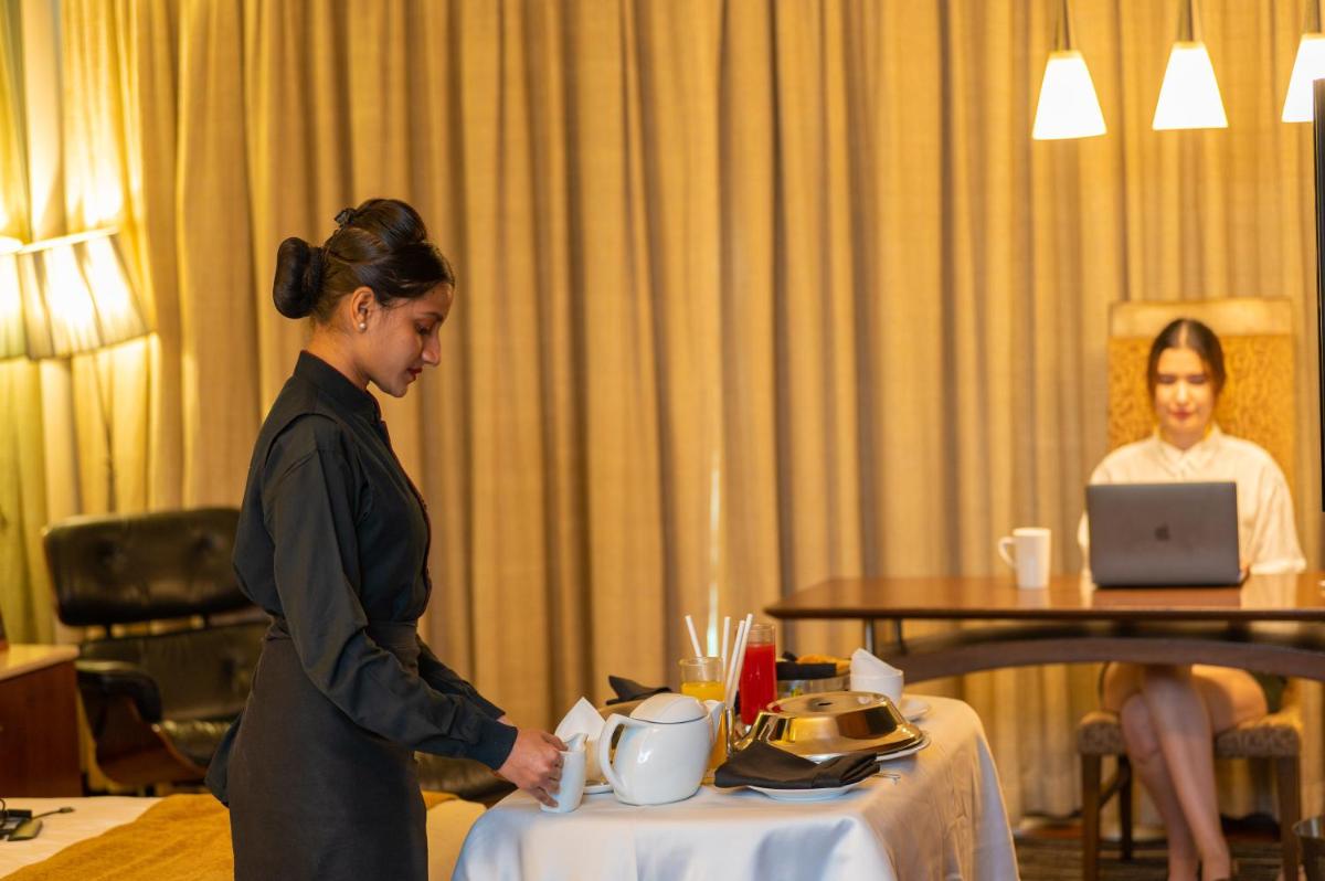 a woman standing next to a table in a hotel room at O Hotel Pune in Pune