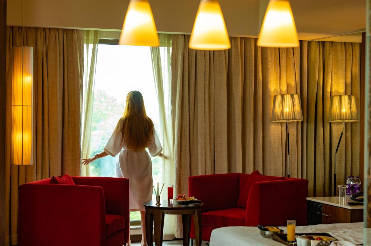 a woman in a hotel room looking out the window at O Hotel Pune in Pune
