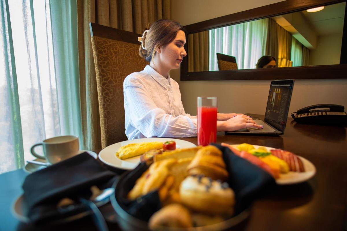 a woman sitting at a table with a plate of food at O Hotel Pune in Pune