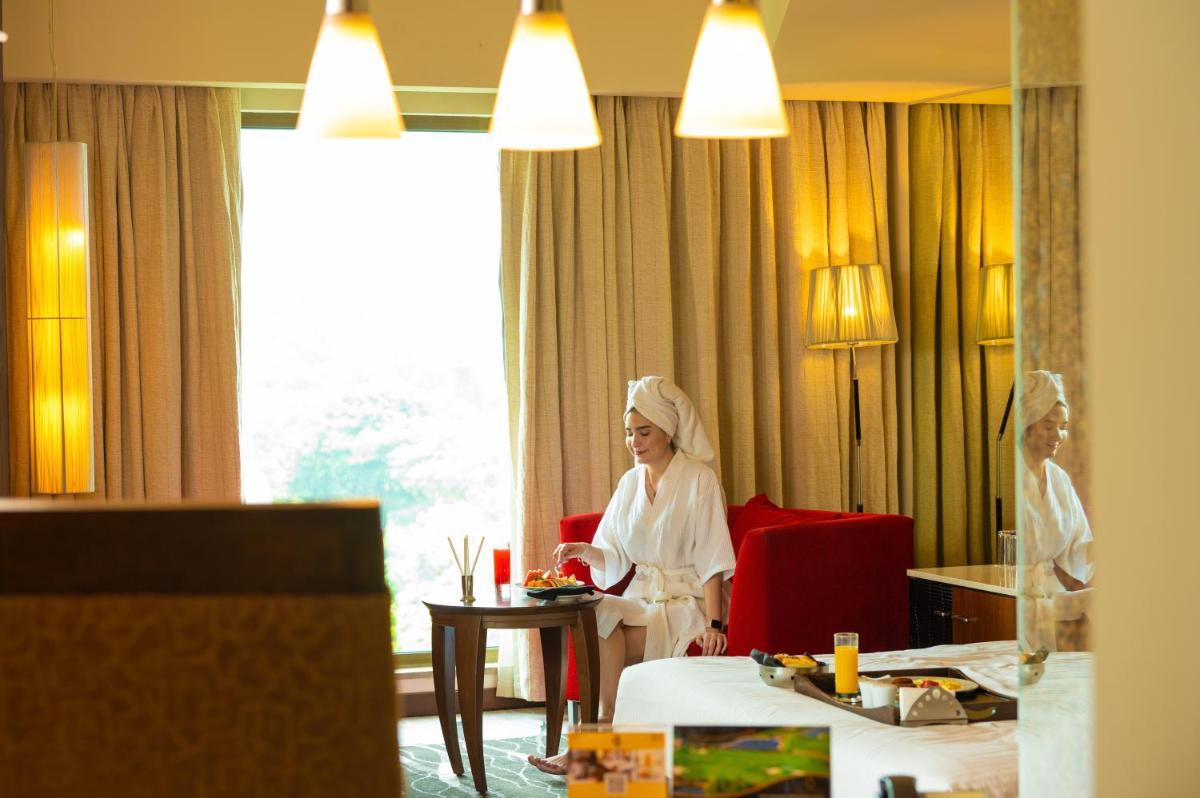 a woman sitting in a red chair in a hotel room at O Hotel Pune in Pune