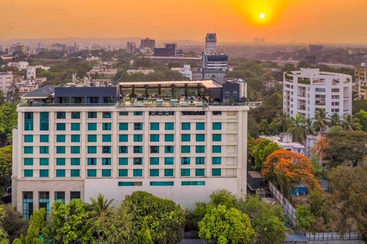 a building in the city with the sunset in the background at O Hotel Pune in Pune