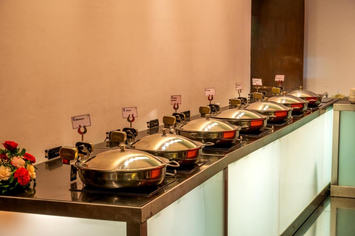 a row of silver pots lined up on a counter at O Hotel Pune in Pune
