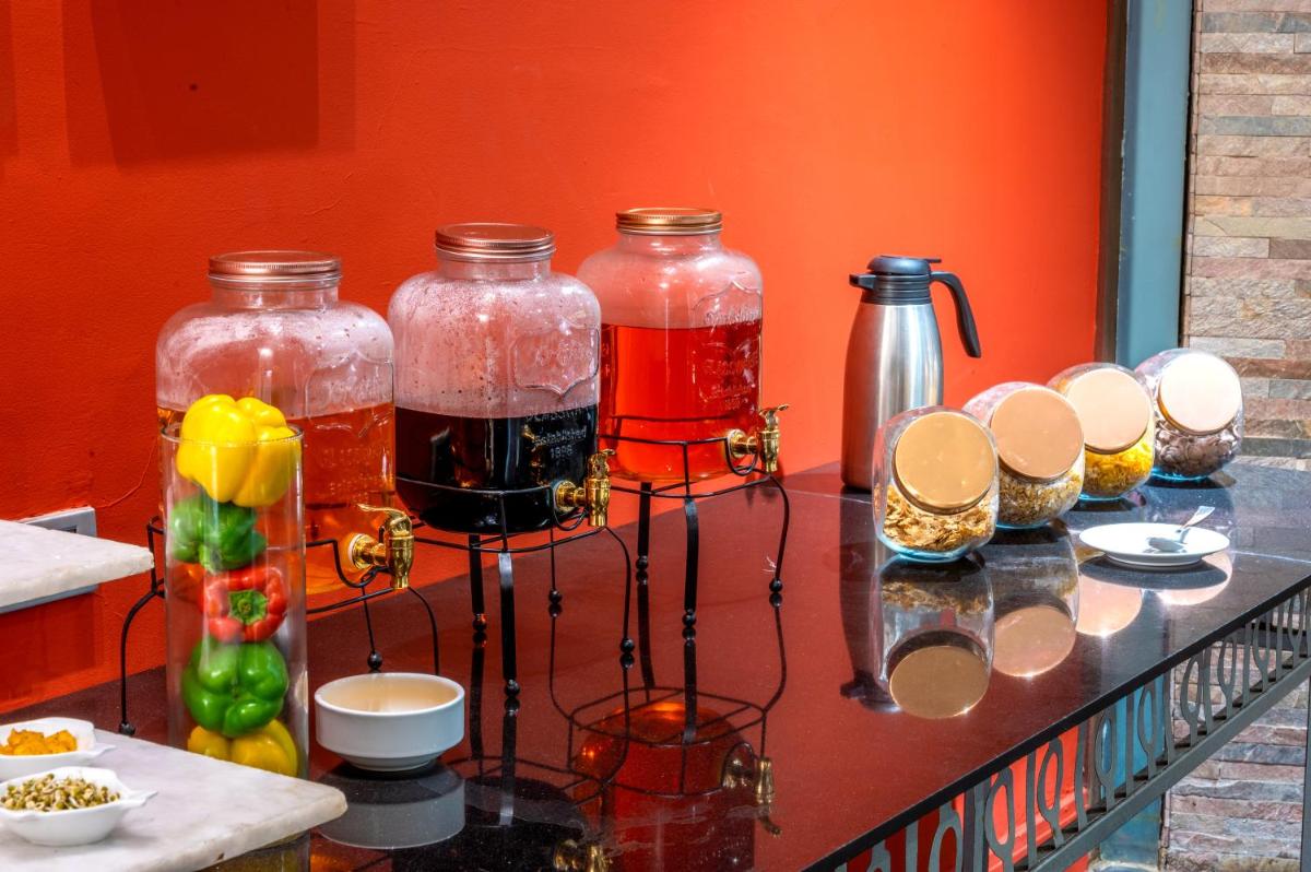 a counter with four glass jars of liquid on it at O Hotel Pune in Pune