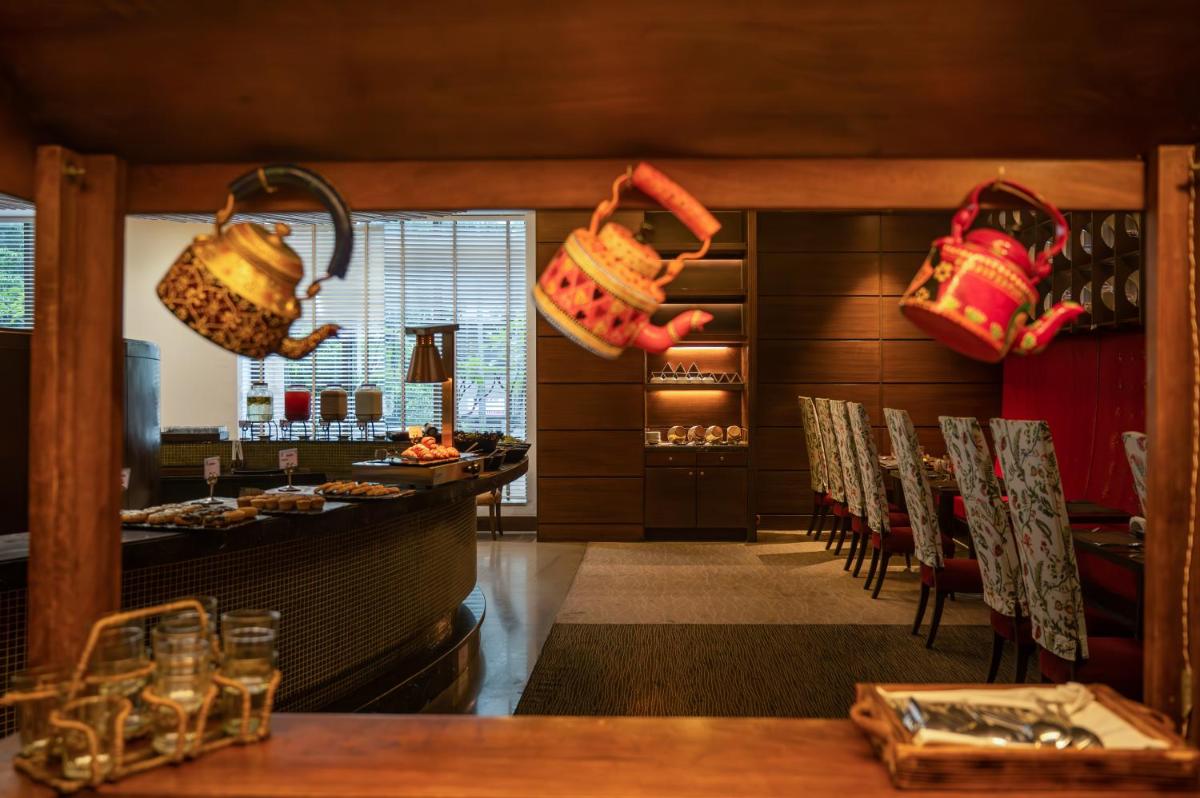 a restaurant with a bar with chairs and hanging baskets at O Hotel Pune in Pune