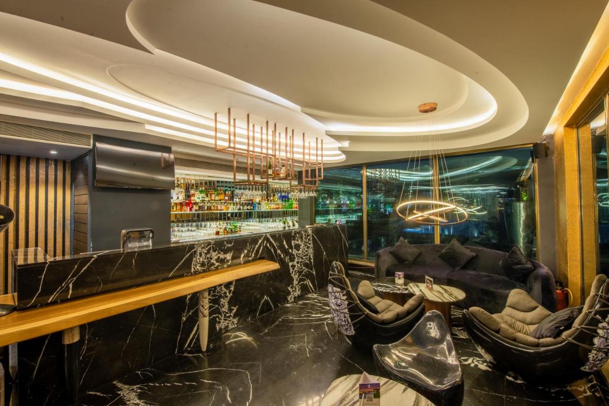 a bar with black leather chairs and a bar counter at O Hotel Pune in Pune